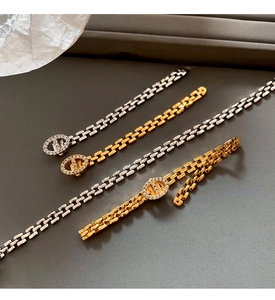 Detail of gold and silver chain bracelets with oval pendants inlaid with sparkling zircons