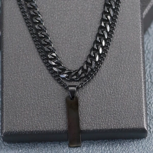 Close-up of black double-layer Cuban chain and cross pendant on a textured gift box