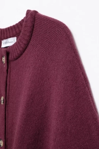 Close-up of ribbed round neck and wood-texture buttons on burgundy knitted cardigan
