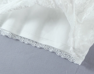 Détail de l'ourlet de robe en dentelle blanche avec motifs floraux et doublure lisse