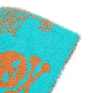 Close-up of cyan and orange faux fur knit beanie with spider web skull and heart patterns