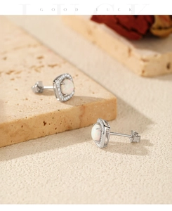 Detailed shot of S925 silver opal stud earrings with zircon halo on stone texture