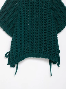 Detail of dark green crochet top with hollow V-pattern texture and side tie accents