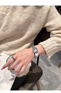 Gros plan d'une montre carrée argentée pour femme avec bracelet en acier et bague élégante