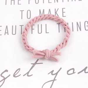Close-up of pink braided elastic hair tie with a delicate knot bow on a text background