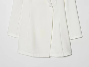 Detailed close-up of the clean hem and smooth drape of a white tailored blazer jacket