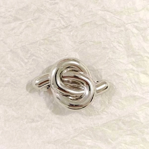 Macro shot of silver knotted metal hair clip on a white textured paper background