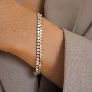 Elegant gold and silver rhinestone tennis necklaces shown on a model neck with a beige blazer