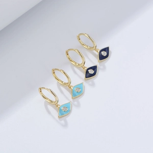 Detail of gold evil eye earrings with blue enamel finish and sparkling white zircon stones