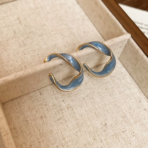 Macro detail of French vintage C-shaped gold hoop earrings with blue enamel finish