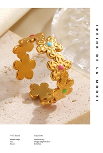 Gros plan d'une bague fleur en acier doré avec pétales en émail coloré sur pierre
