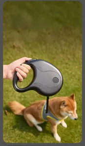 Ergonomic D-shaped handle of the black retractable dog leash used on a Shiba Inu outdoors