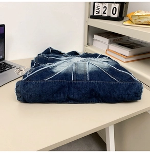 Detail of vintage blue patchwork denim tote bag with frayed edges in a lifestyle office setting
