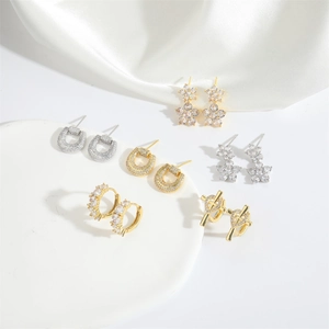 Set of gold and silver vintage cross heart and floral stud earrings on white pedestal