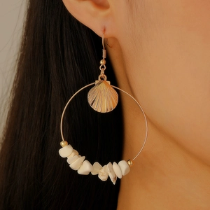 Detailed close-up of a gold shell hoop earring with natural white stone accents