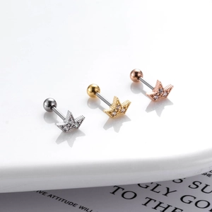 Close-up of star-shaped cartilage studs in silver, gold, and rose gold with tiny zircons
