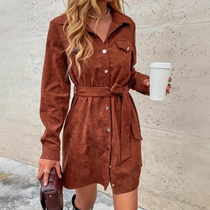 Detail of tan corduroy shirt dress featuring metal buttons and a matching waist belt