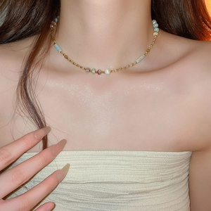 Détail de perles colorées sur le collier ras du cou doré porté par un mannequin femme