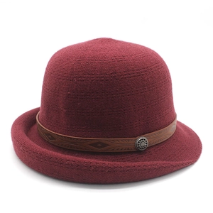 Detail of burgundy knitted hat with retro geometric pattern leather band and metal button