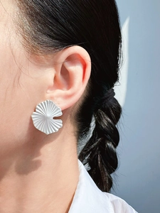 Close-up of elegant ginkgo leaf earrings with a polished silver finish on a model