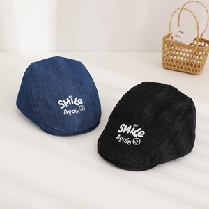 Detail of blue and black denim berets with smile again embroidery and cotton texture