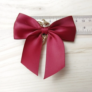 Close-up of red ribbon bow keychain with golden ring showing 9cm width measurement