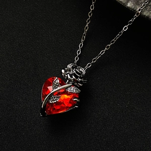Close-up of gothic silver rose winding around a red heart crystal pendant on chain