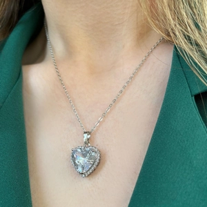 Minimalist silver heart pendant necklace with zircon crystals worn on dark suit jacket