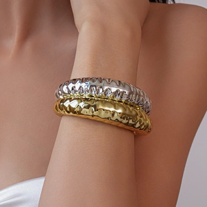 Detail of layered gold and silver irregular acrylic bangles with a molten lava texture