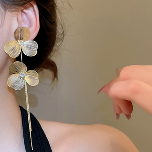 Close-up of golden floral tassel earrings with zircon inlay worn on a female model