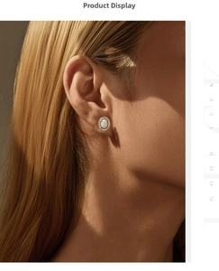Close-up of elegant oval opal earrings with sparkling zircon halo on model's ear