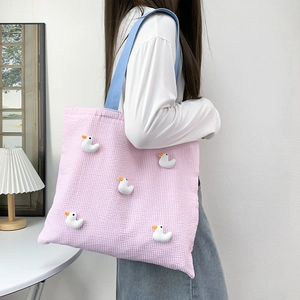 Detailed view of pink seersucker striped tote bag featuring 3D white plush ducklings