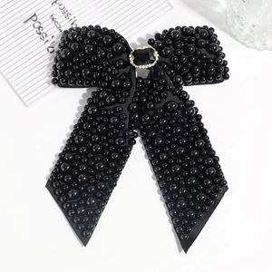 Close-up of black fabric bow hair clip with faux pearls and rhinestone center detail