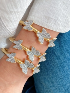 Close-up of three gold butterfly open cuffs with micro-paved white zircons on a model