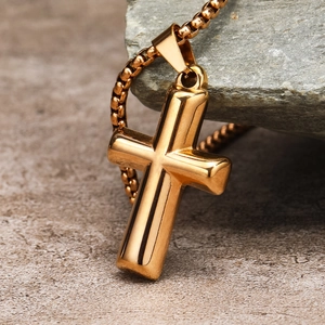 Macro shot of polished gold stainless steel cross pendant on a matching chain
