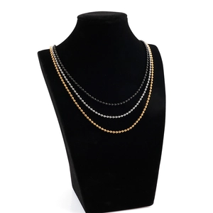 Vue détaillée des chaînes à billes en acier noir, argent et or sur un buste de mannequin
