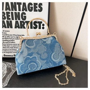 Close-up of blue denim handbag featuring a gold metal kiss-lock frame with rhinestones
