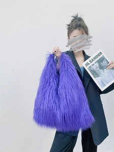 Detail view of purple faux fur tote bag carried by a model in a black blazer