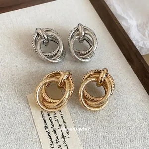 Irregular multilayer silver needle earrings in gold and silver finish on textured fabric