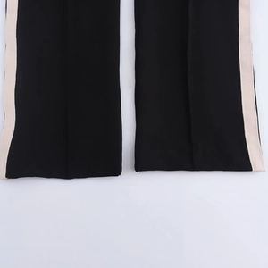 Detailed macro view of the black sports pants hem featuring side beige stripe accents