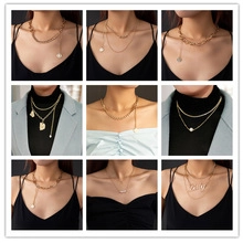 Detail shot of a woman wearing layered gold necklaces with pearl and coin pendants