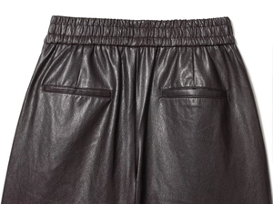 Detail of faux leather shorts featuring elastic waistband and two welt back pockets