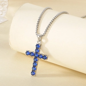 Detailed macro view of silver box chain necklace with blue pavé stone cross pendant