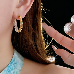 Gros plan d'une boucle d'oreille créole dorée avec perles en cristal sur un mannequin