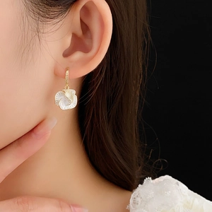 Macro detail of gold-plated flower zircon earring worn on a model's earlobe