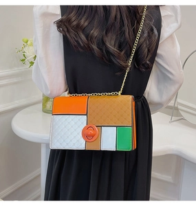 Detail of color-block handbag with quilted texture and gold chain strap worn by a model