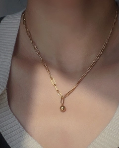 Detail of 18K gold plated asymmetric chain necklace with minimalist gold ball pendant