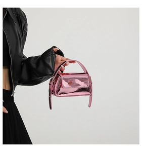 Macro shot of metallic pink patent leather finish and flap closure on small handbag