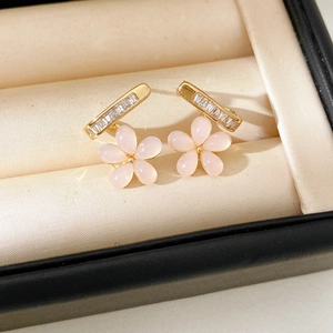Detail of gold floral earrings with pink resin petals and sparkling zircon accents