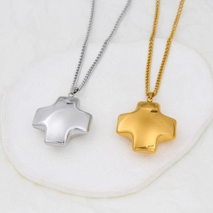 Minimalist gold and silver titanium steel cross pendant necklaces on white stone tray